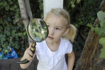 Junges Mädchen schaut durch Vergrößerungsglas — Stockfoto