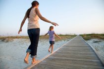 Mother and daughter walking on beach walkway — Stock Photo