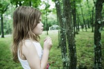 Girl blowing bubbles in forest — Stock Photo