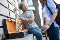 Città del Capo, Sud Africa, yoing uomo imballaggio via il suo sassofono mentre chatta con il suo membro della band — Foto stock