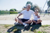 Grandfather and grandson sitting on sports field — Stock Photo