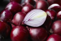 Fresh whole red onions and one halved on table — Stock Photo