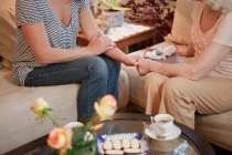 Senior woman and daughter holding hands on sofa — Stock Photo