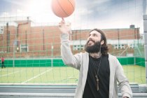 Mid adult man spinning basketball on finger — Stock Photo