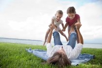Daughters balancing on feet of mother — Stock Photo