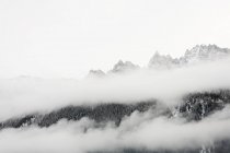 Clouds surrounding rocky mountains, black and white — Stock Photo