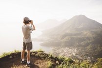 Junger Mann fotografiert am atitlan-see mit digitalkamera, guatemala — Stockfoto