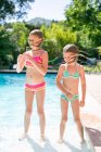 Two sisters shaking wet hair by outdoor swimming pool — Stock Photo