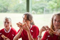 Girl soccer players eating pizza — Stock Photo