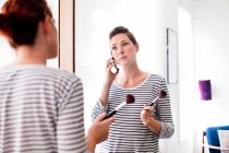 Woman on cell phone applying make up — Stock Photo