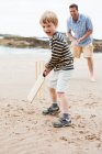 Father and son playing cricket on beach — Stock Photo