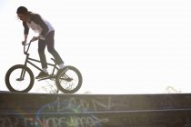 Jeune homme faisant cascade sur bmx à skatepark — Photo de stock