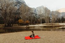 Woman sitting on red blanket looking out at landscape, Yosemite National Park, California, USA — Stock Photo