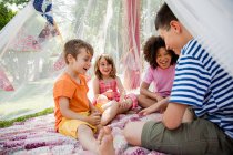 Four friends in summer netting tent — Stock Photo