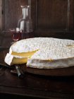 Wheel of brie cheese on wooden board with wine — Stock Photo