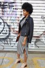 Joven blogger de moda con cabello afro by graffiti wall, Nueva York, EE.UU. - foto de stock