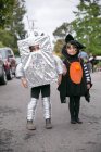 Portrait of boy in robot costume and girl in witch costume on street — Stock Photo