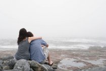 Visão traseira do casal abraçando na praia rochosa — Fotografia de Stock