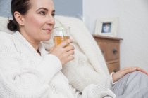 Mulher relaxando em casa, tomando uma bebida — Fotografia de Stock