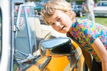 Мальчик смотрит в зеркало крыла автомобиля — стоковое фото