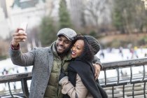 Romantic happy couple enjoying city during winter holidays taking selfies by ice skating rink — Stock Photo