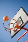 Ballon de basket et cerceau sur ciel bleu clair — Photo de stock