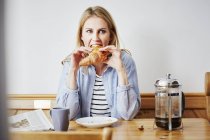 Femme adulte moyenne mangeant croissant — Photo de stock