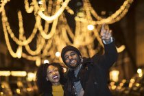 Casal feliz romântico desfrutando da cidade durante as férias de inverno olhando para luzes de férias ao ar livre — Fotografia de Stock