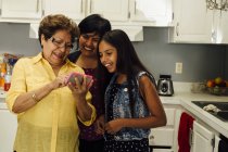 Mehrgenerationenfamilie blickt aufs Smartphone und lächelt — Stockfoto