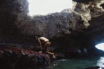 Junge Frau klettert auf Felsen, Mermaid Caves, Oahu, Hawaii, USA — Stockfoto