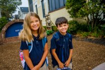 Portrait of male and female twins outside elementary school — Stock Photo