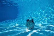 Alarm clock on bottom of pool — Stock Photo