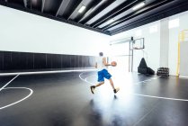 Вид ззаду чоловічий баскетболіст, що бігає з м'ячем на баскетбольній практиці — стокове фото