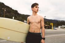 Porträt eines jungen Mannes mit Surfbrett — Stockfoto