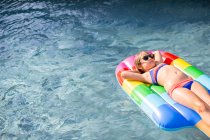 Menina de biquíni deitada sobre inflável na piscina exterior — Fotografia de Stock