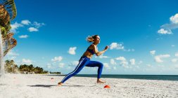 Обучение молодых женщин, бег между тренировочными конусами на пляже — стоковое фото