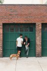 Young male couple with dog leaning on garage eating ice cream cones — Stock Photo