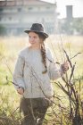 Молодая женщина в шляпе трогает растения в поле — стоковое фото
