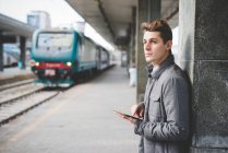 Portrait of young businessman commuter using digital tablet at train station. — Stock Photo