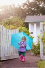 Bambino femmina che cammina in giardino portando ombrello — Foto stock
