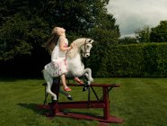 Uma jovem menina em um cavalo balançando — Fotografia de Stock