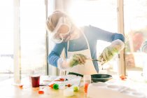 Menina fazendo experiência científica, derramando líquido verde na frigideira — Fotografia de Stock