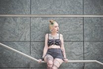 Retrato de jovem fêmea tatuado punk sentado no metro corrimão — Fotografia de Stock