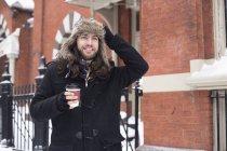 Junger Mann schlendert durch die Straße und trinkt Kaffee zum Mitnehmen — Stockfoto