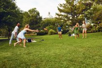 Five adult friends playing with flying disc in park — Stock Photo