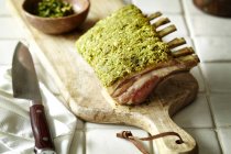 Rack of lamb with herb crust on chopping board — Stock Photo