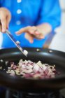 Close-up partial view of woman frying onion, selective focus — Stock Photo