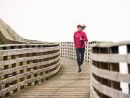 Жінка біжить на дерев'яному причалі — стокове фото