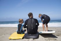 Vue arrière de père et deux fils pratiquant avec des bodyboards sur la plage, Laguna Beach, Californie, États-Unis — Photo de stock