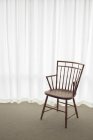 Порожній дерев'яний стілець з білими шторами на фоні — стокове фото